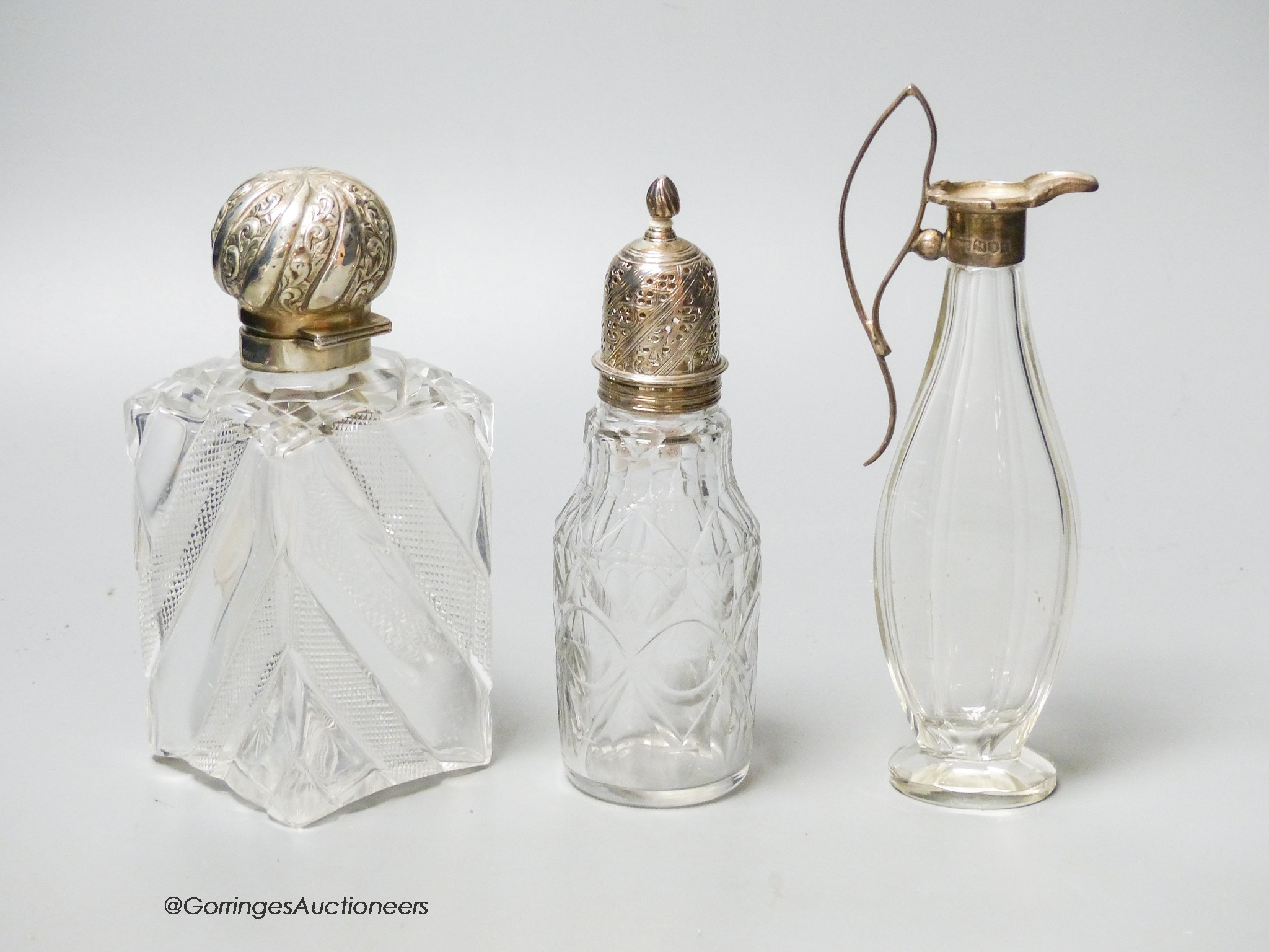 A late Victorian silver topped cut glass scent bottle, London, 1890, 15cm, a later silver mounted glass condiment ewer and silver mounted glass caster.